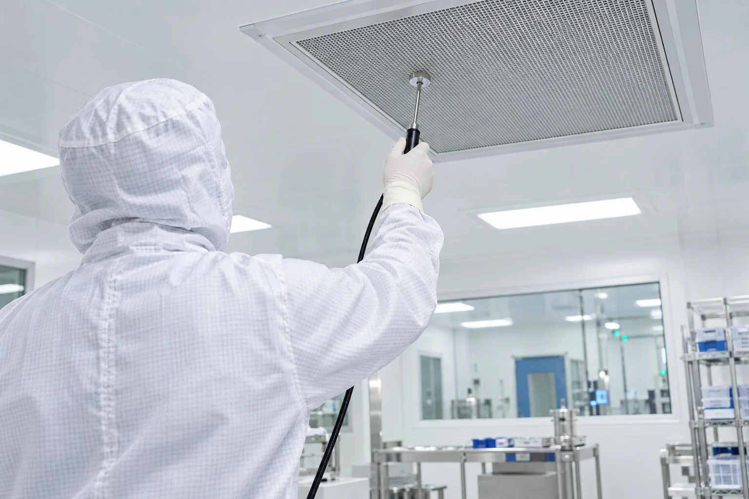 Technicien contrôlant un filtre de plafond en salle propre